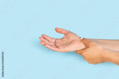 Mano de mujer con dolor de muñeca sobre un fondo celeste pastel liso y aislado. Visat de frente y de cerca. Copy space. Concepto: padecer el síndrome del túnel carpiano
