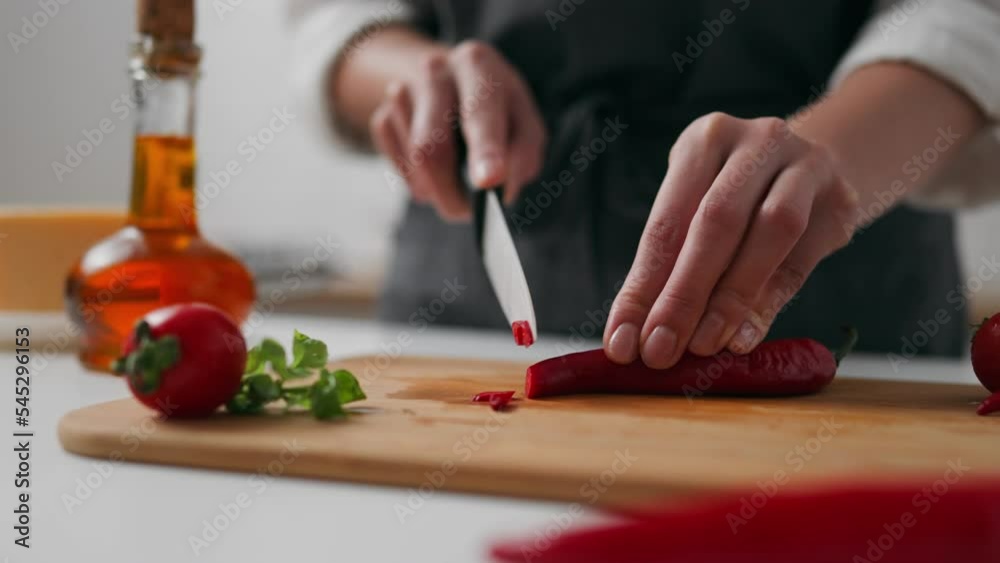 Woman cook focused in the distance cuts red chili pepper hot red pepper on a cutting board made of wood, Hands holding pepper cooking dressing additive stuffing
Woman cook focused in the distance cuts red chili pepper hot red pepper on a cutting board made of wood, Hands holding pepper cooking dressing additive stuffing