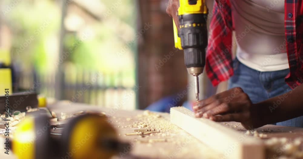 Young woman using a screwdriver on a piece of wood while working in a workshop