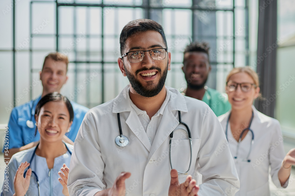 Successful team of medical doctors are looking at camera and smiling while standing in hospital Successful team of medical doctors are looking at camera and smiling while standing in hospital