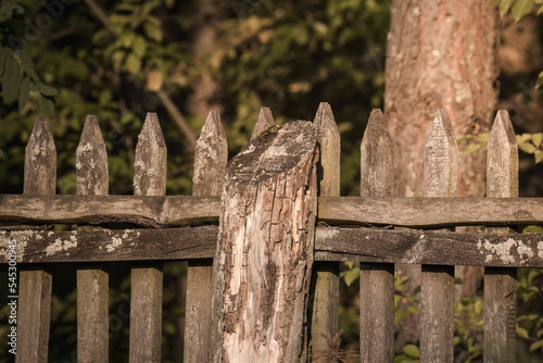 A very old wooden fence in the countryside, a fence made of wide, chopped boards, old boards, historic wooden structure, a brown fence
