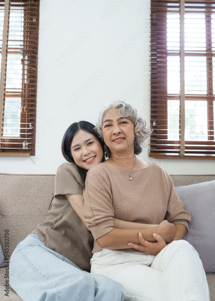 Portrait loving adult asian people daughter and senior mature mom hugging on couch. Portrait loving adult asian people daughter and senior mature mom hugging on couch.