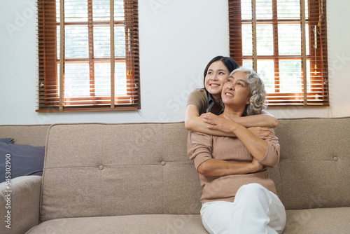 Asian family mother daughter give hug cuddle embrace at home sofa, Grown up daughter hugging elderly mother feeling love.