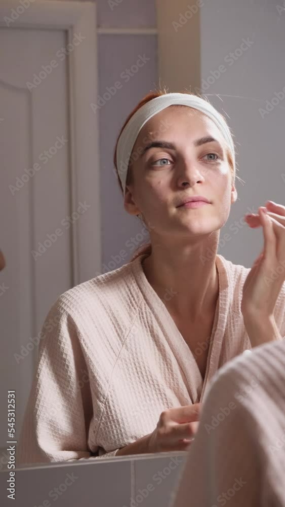Beauty Day. A woman who takes care of her skin daily in the bathroom in front of a mirror, gently apply anti-aging collagen serum to her face and neck. The concept of beauty, self-care, cosmetics