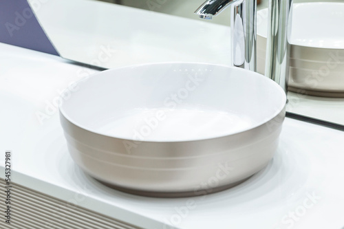 Faucet for water over a white sink. Close-up. Selective focus. Stylish interior.