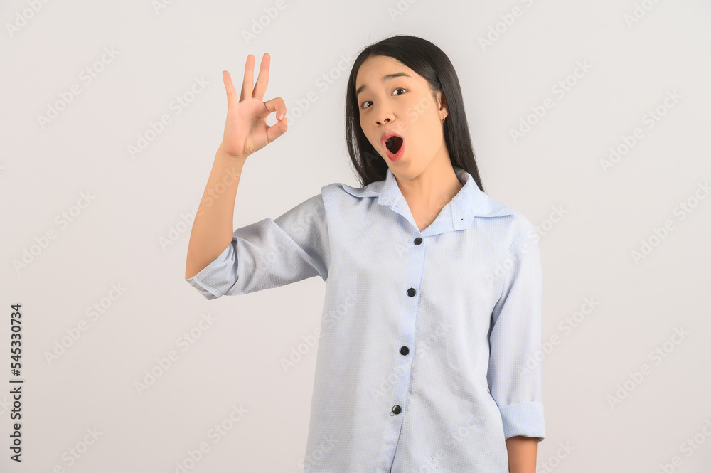 Portrait of young asian woman doing ok sign with hand and fingers over isolated white background Portrait of young asian woman doing ok sign with hand and fingers over isolated white background
