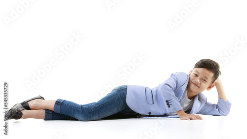 A 10-year-old Asian boy in a casual jacket is lying on the floor and smiling happily in a good mood looking at the camera. Positive concepts for children and young men's lifestyles.