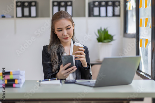 Photo of adorable young Asian lady hold telephone look screen palm keyboard shirt in home office indoors at the workplace  