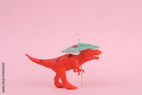 Toy dinosaur tyrannosaurus rex with umbrella on pink background. Minimalism creative layout © splitov27