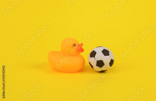 Rubber duck with a soccer ball on a yellow background
