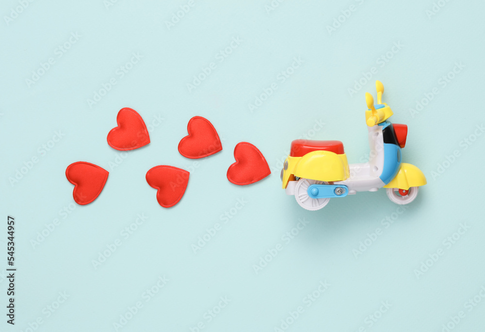 Toy moped with hearts on bue background. Romantic, love concept