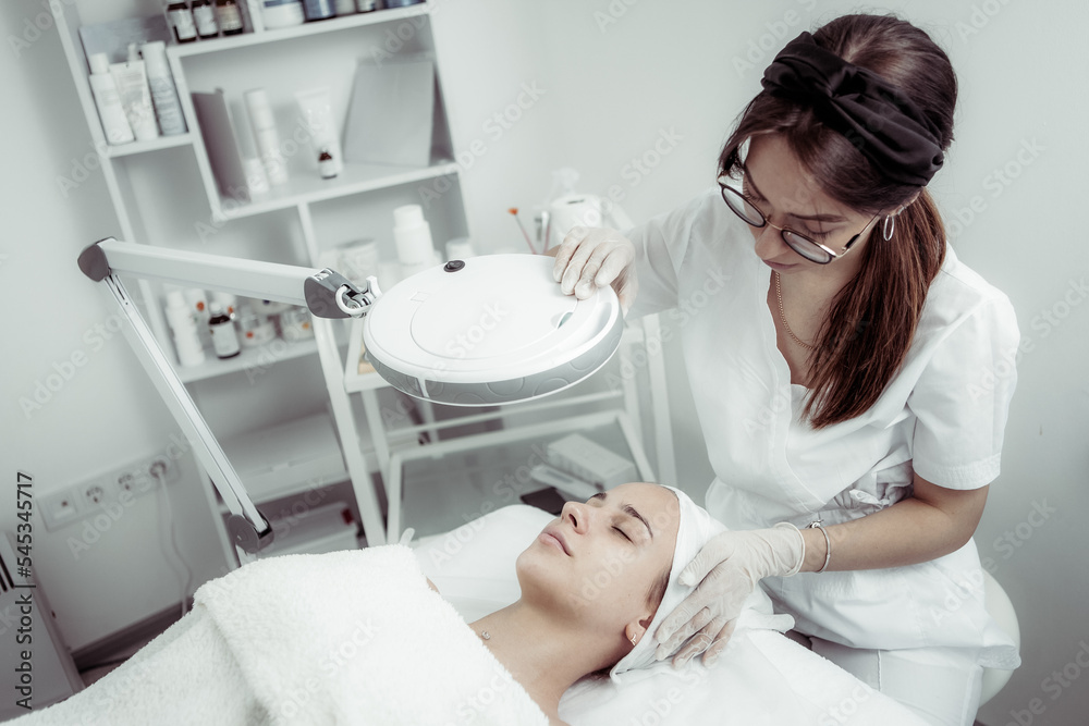 Skincare treatment. Dermatologist carefully examines the client's face before the cosmetic procedure in beauty salon Skincare treatment. Dermatologist carefully examines the client's face before the cosmetic procedure in beauty salon
