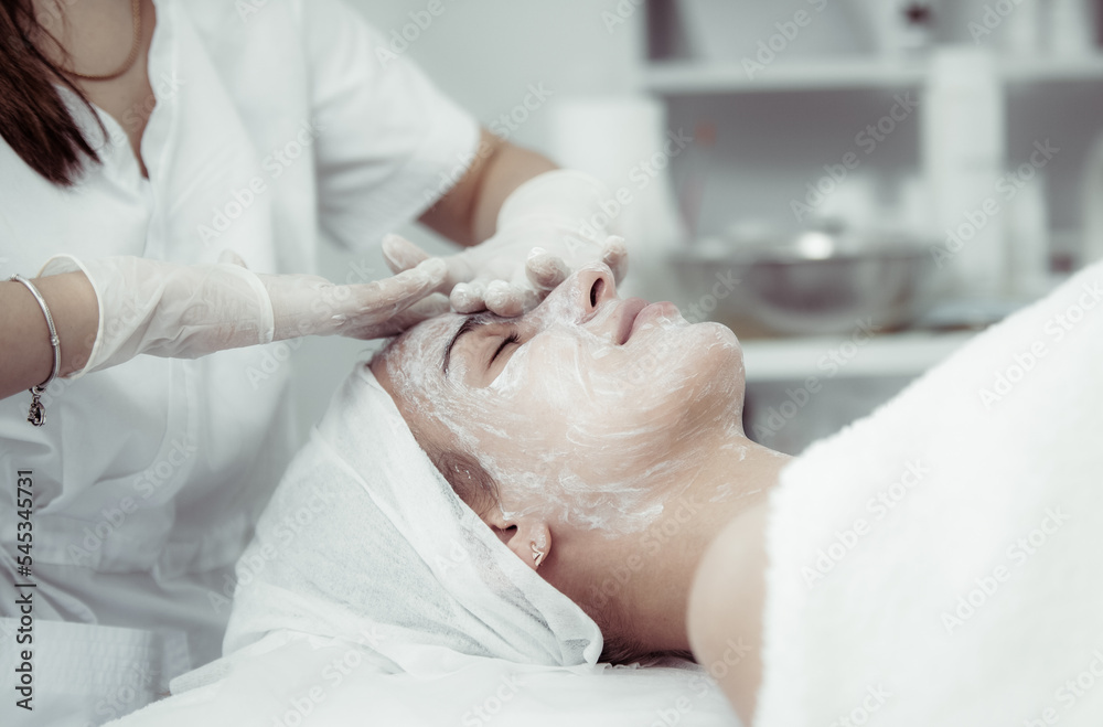 Facial skin care procedures. Beautician makes massage procedure with beauty woman's face in cosmetic clinic Facial skin care procedures. Beautician makes massage procedure with beauty woman's face in cosmetic clinic