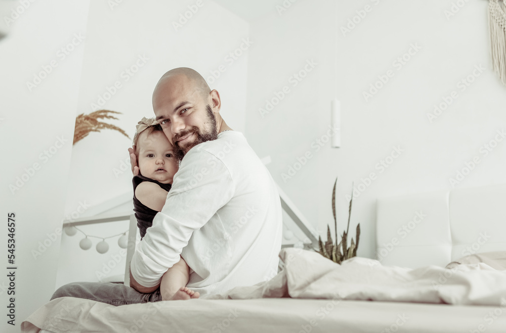 Caring father hugs his little daughter on the bed in bedroom. Love and care, happy family, spending time together concept