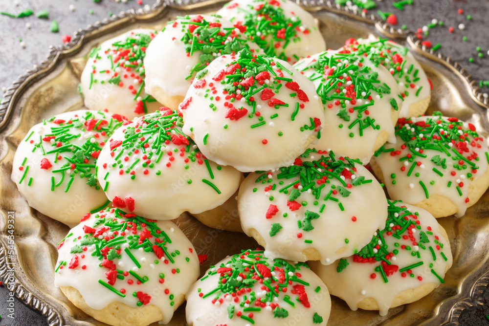 Italian Christmas Cookies a soft and sweet cake-like cookie covered with icing and sprinkles closeup in the plate on the table. Horizontal Italian Christmas Cookies a soft and sweet cake-like cookie covered with icing and sprinkles closeup in the plate on the table. Horizontal