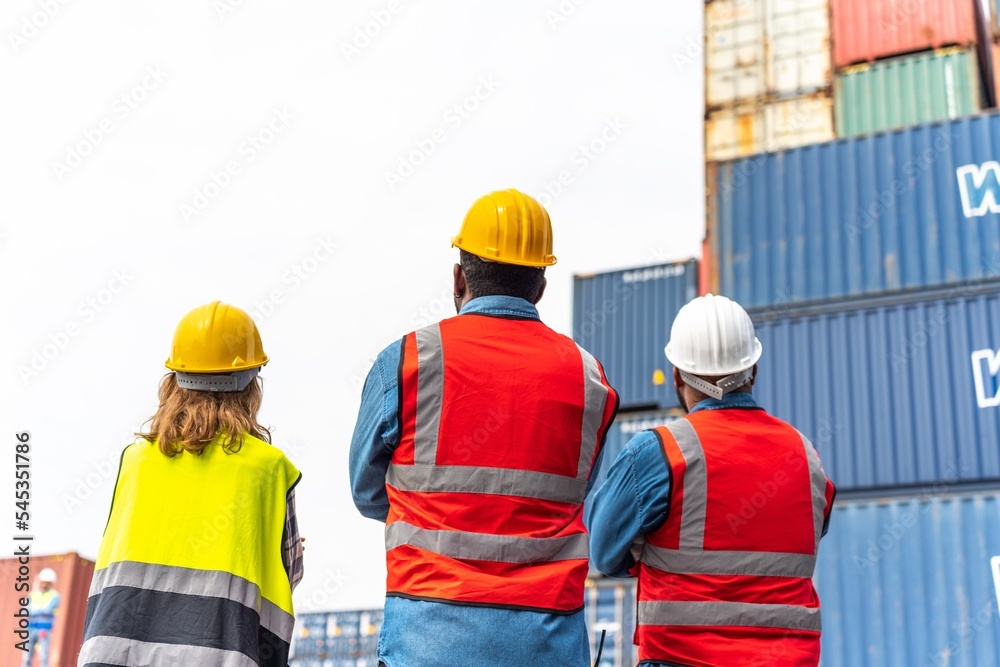 Photo of the backside of a team of engineers of male and female holding hand together looking towards with determination and hope in front a stacks full of containers in a container shipping dock yard Photo of the backside of a team of engineers of male and female holding hand together looking towards with determination and hope in front a stacks full of containers in a container shipping dock yard