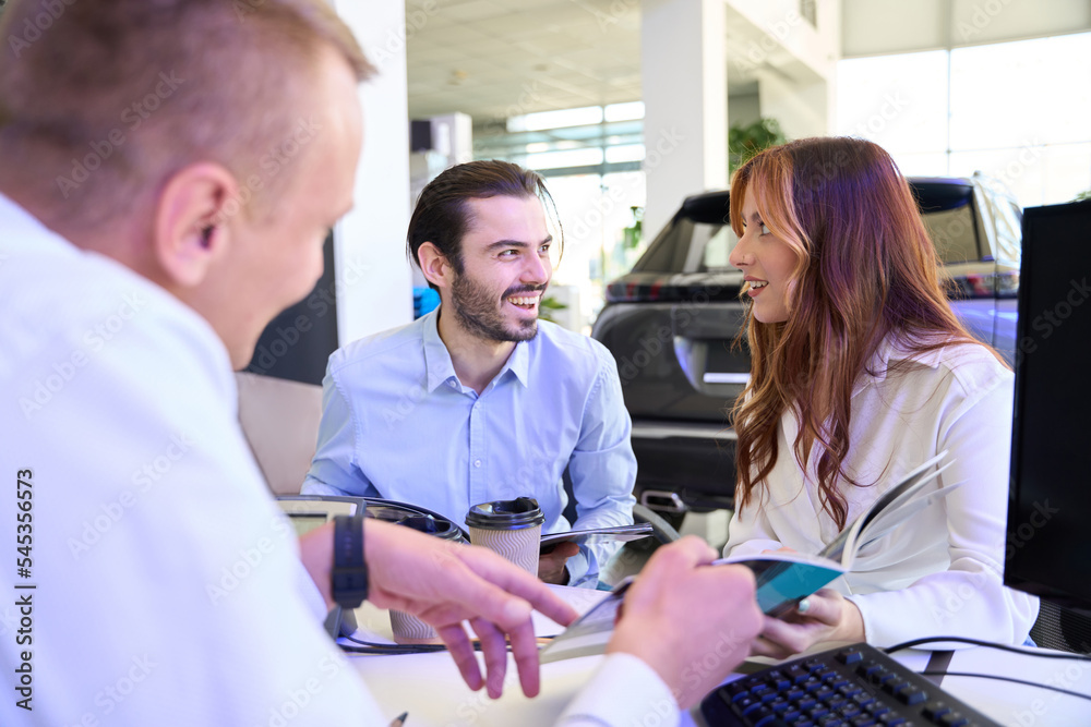 Obraz premium Experienced auto sales representative advising young couple