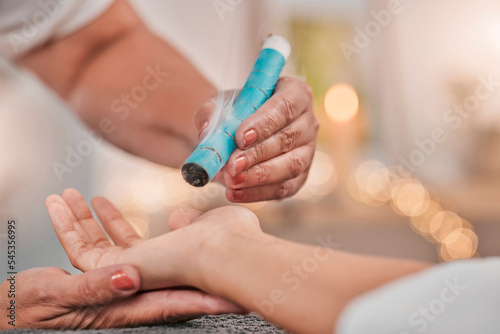 Spa  therapy and hand of therapist using smoke and leaves for physical therapy with moxibustion while burning leaves on patient. Woman getting heat therapy with plant for health and wellness of body