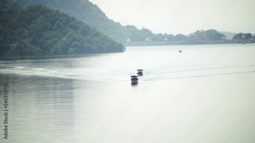 aerial drone shot showing two boats approaching on tranquil empty Dhebar lake jaisamand with aravalli hills in the background with fog over the water in this tourist holiday destination aerial drone shot showing two boats approaching on tranquil empty Dhebar lake jaisamand with aravalli hills in the background with fog over the water in this tourist holiday destination