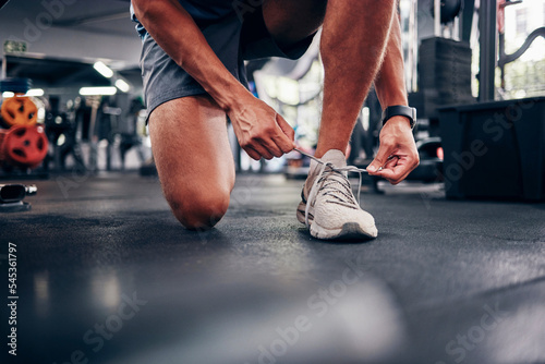 Hands  gym and man tie shoes preparing for training  running or exercise. Sports  fitness or male athlete in health studio getting ready for cardio  workout or bodybuilding practice in fitness center