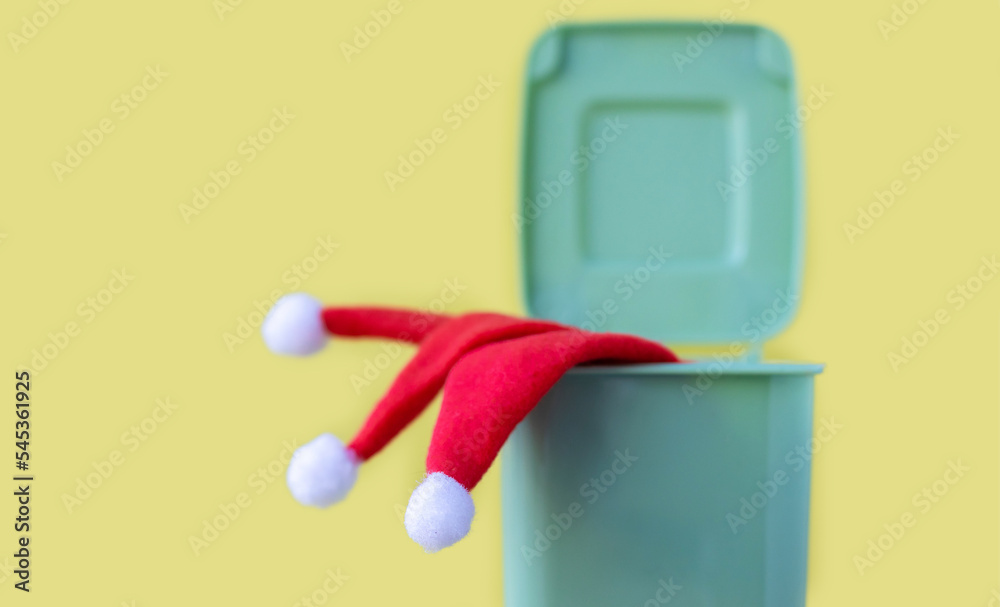 red color small lsanta cap hat throw away dropped off in mini trash bin can garbage waste.christmas holiday is over or against celebration.santa claus robe clothes happy new year isolated yellow red color small lsanta cap hat throw away dropped off in mini trash bin can garbage waste.christmas holiday is over or against celebration.santa claus robe clothes happy new year isolated yellow