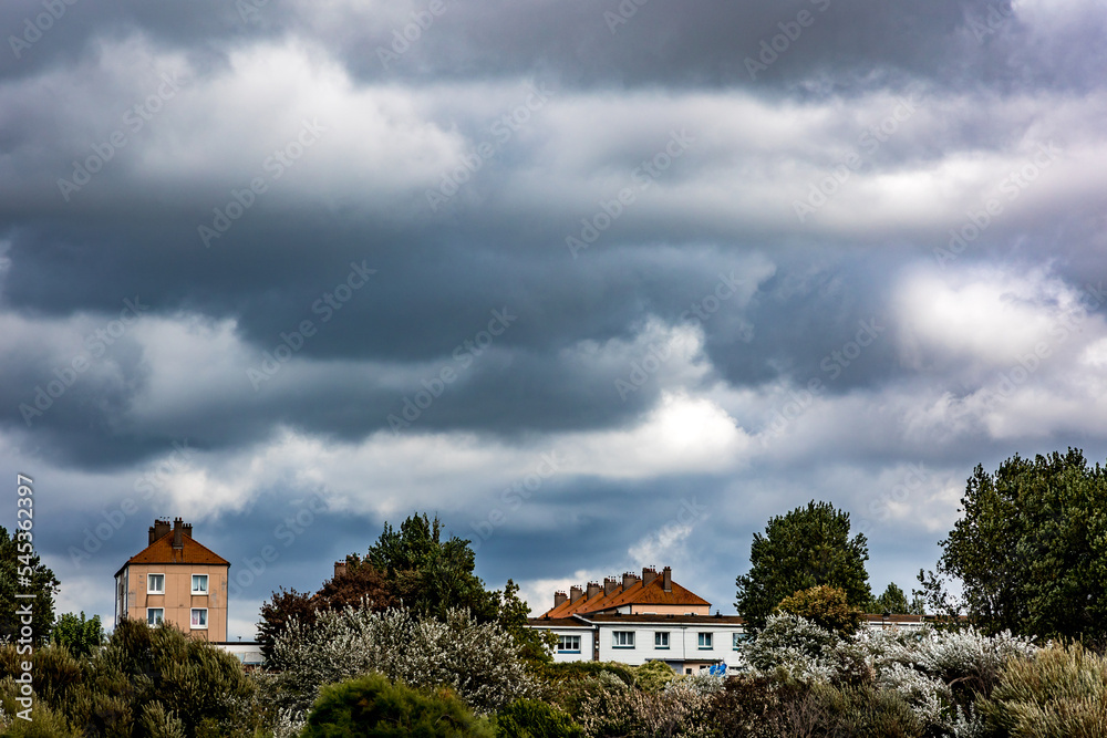 Ciel chargé et menaçant au dessus des maisons et jardins