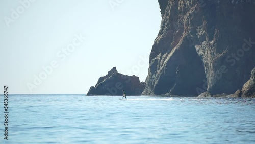 A motorized surfboard with a rider moving on a calm sea. The silhouette of a man on a water scooter glides through the water. Sports and sea activities on a beach holiday. Slow motion. photo