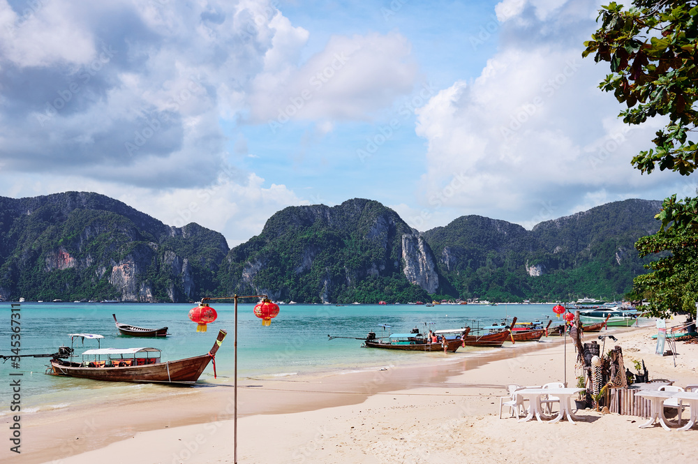 Beautiful landscape with traditional longtail boats, rocks, cliffs, tropical white sand beach. Traveling by Thailand.