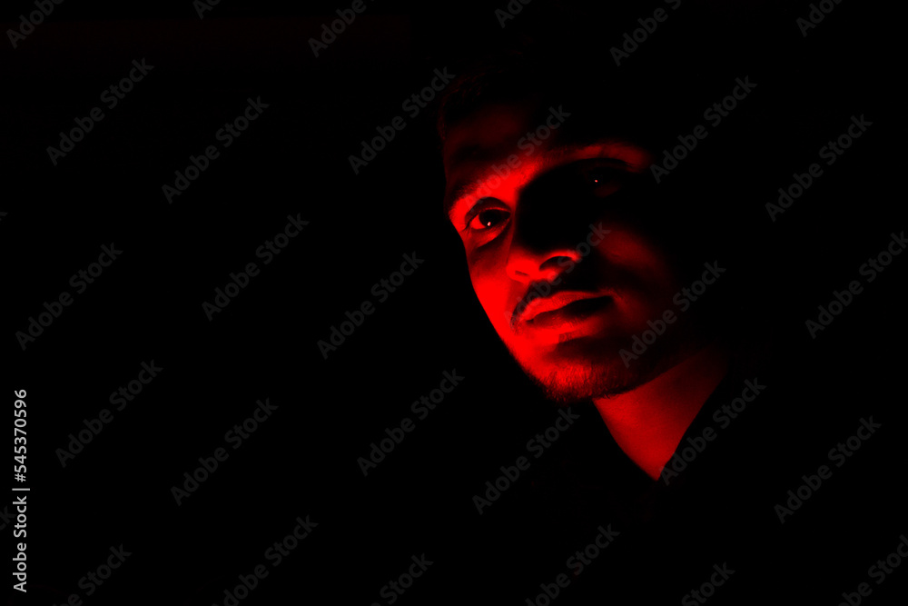 Portrait face of a young Indian guy, with red color light in the dark. Portrait face of a young Indian guy, with red color light in the dark.