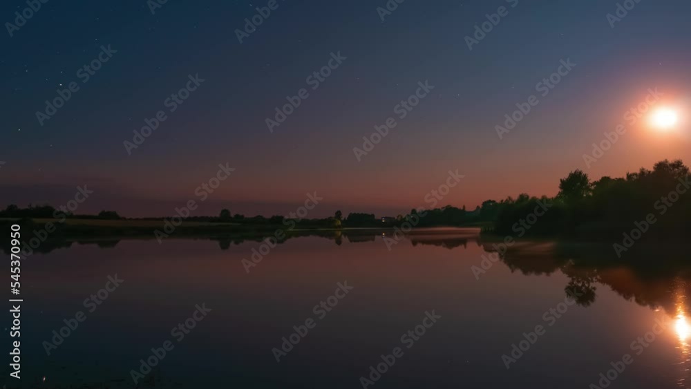 Timelapse of night sky above a calm lake with flat water surface