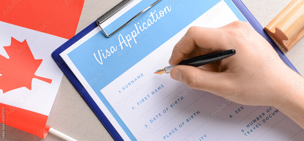Woman filling in visa application form at table, closeup. Concept of immigration Woman filling in visa application form at table, closeup. Concept of immigration
