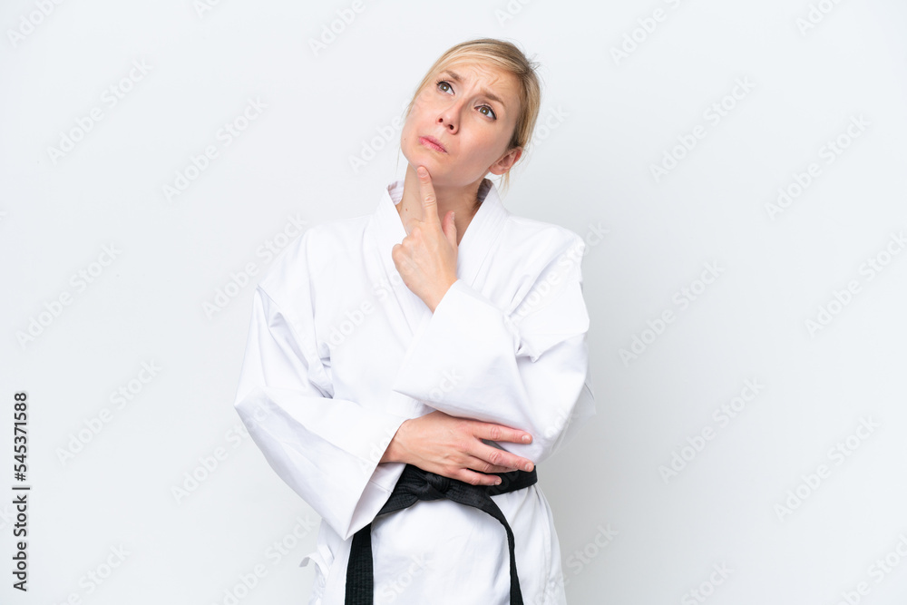 Young caucasian woman doing karate isolated on white background having doubts while looking up Young caucasian woman doing karate isolated on white background having doubts while looking up