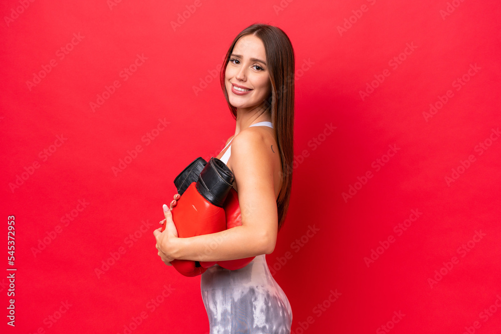 Young beautiful caucasian woman isolated on red background with boxing gloves