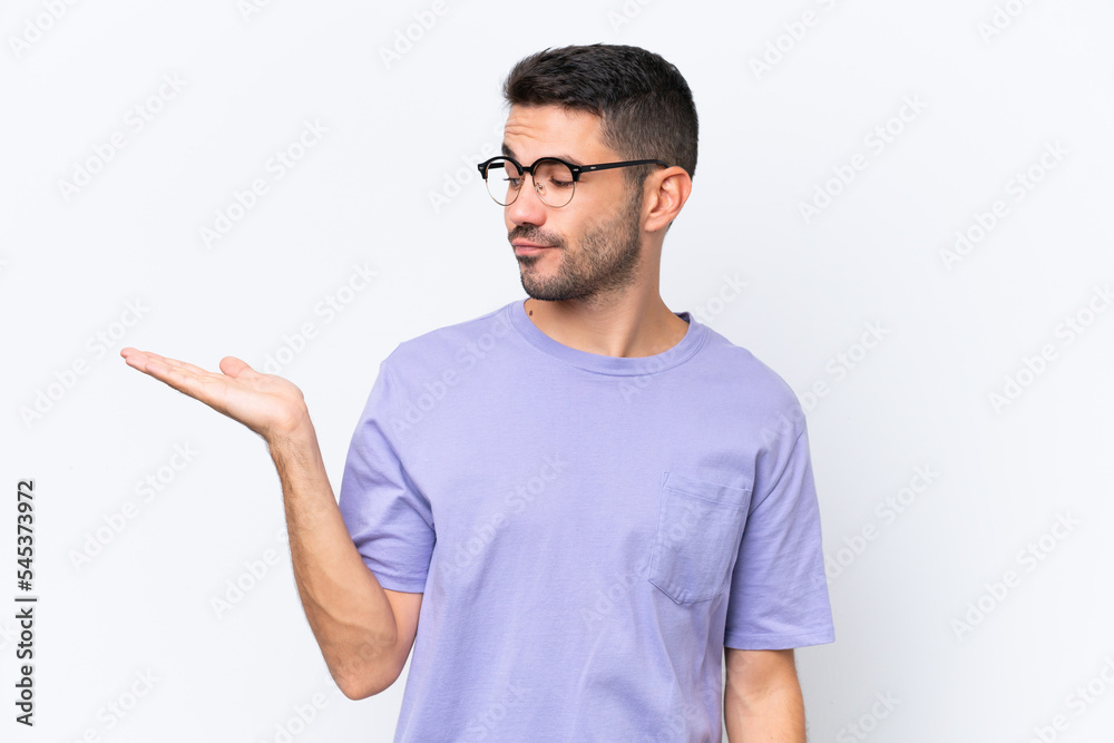 Young caucasian man isolated on white background holding copyspace with doubts