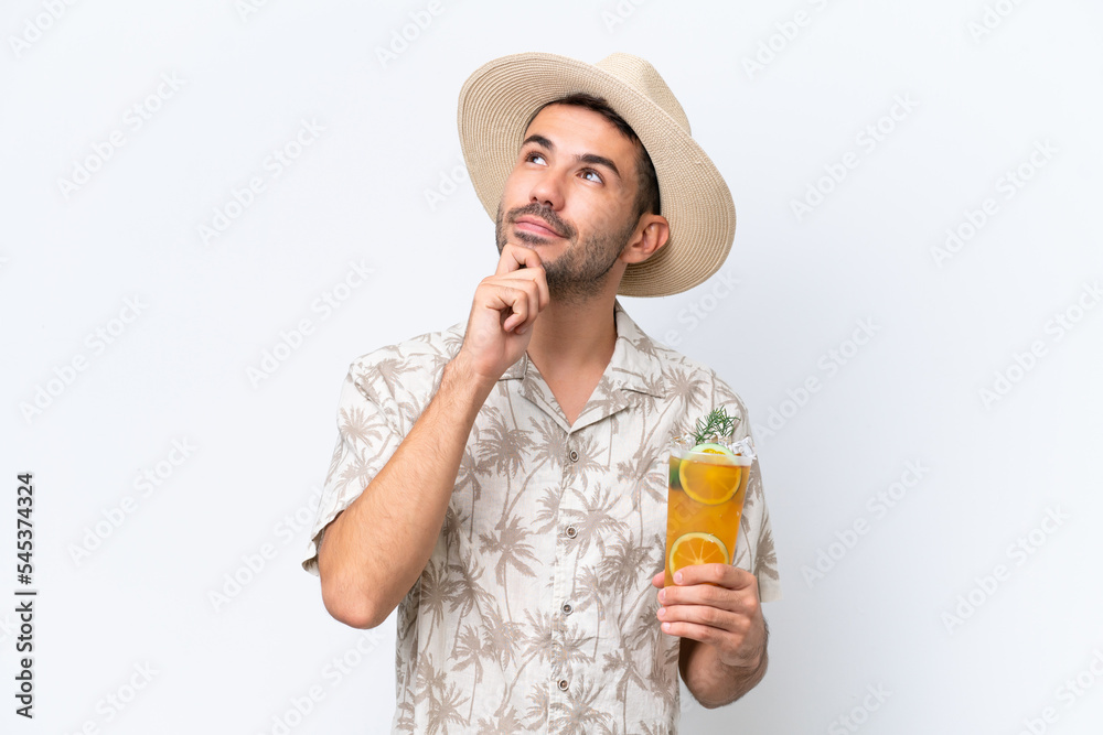 Fototapeta premium Young caucasian man holding a cocktail isolated on white background and looking up