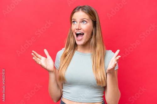 Young beautiful woman isolated on red background with surprise facial expression © luismolinero