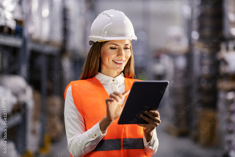 A happy storage manager is using tablet in facility and smiling at it. A happy storage manager is using tablet in facility and smiling at it.