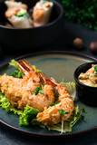 Asian fried shrimp in almond flakes with lettuce and vegetable dressing with spring rolls with shrimps, cucumbers, rice and cashew nuts with sauce and greens.