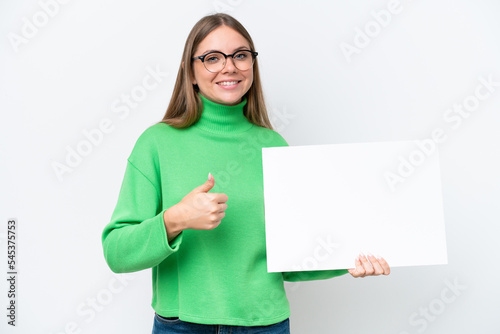 Young caucasian woman isolated on white background holding an empty placard with thumb up