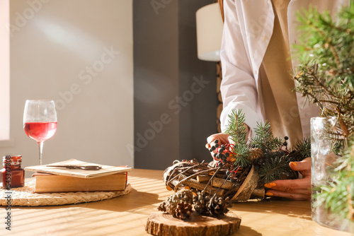 Woman making Christmas wreath at wooden table, closeup