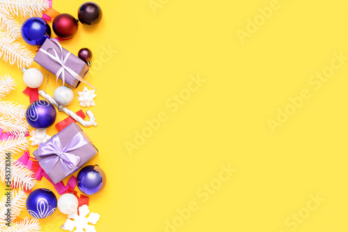 Composition with Christmas gifts, decorations and confetti on yellow background