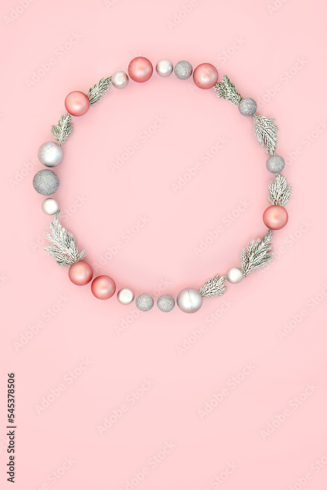 Obraz premium Christmas wreath with winter snow fir and tree bauble ornaments on pastel pink background. Festive abstract minimal design concept for winter Xmas and New Year. 