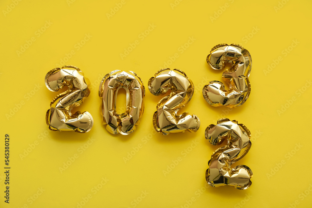 Figure 2022 made of balloons replaced by 2023 on yellow background Figure 2022 made of balloons replaced by 2023 on yellow background