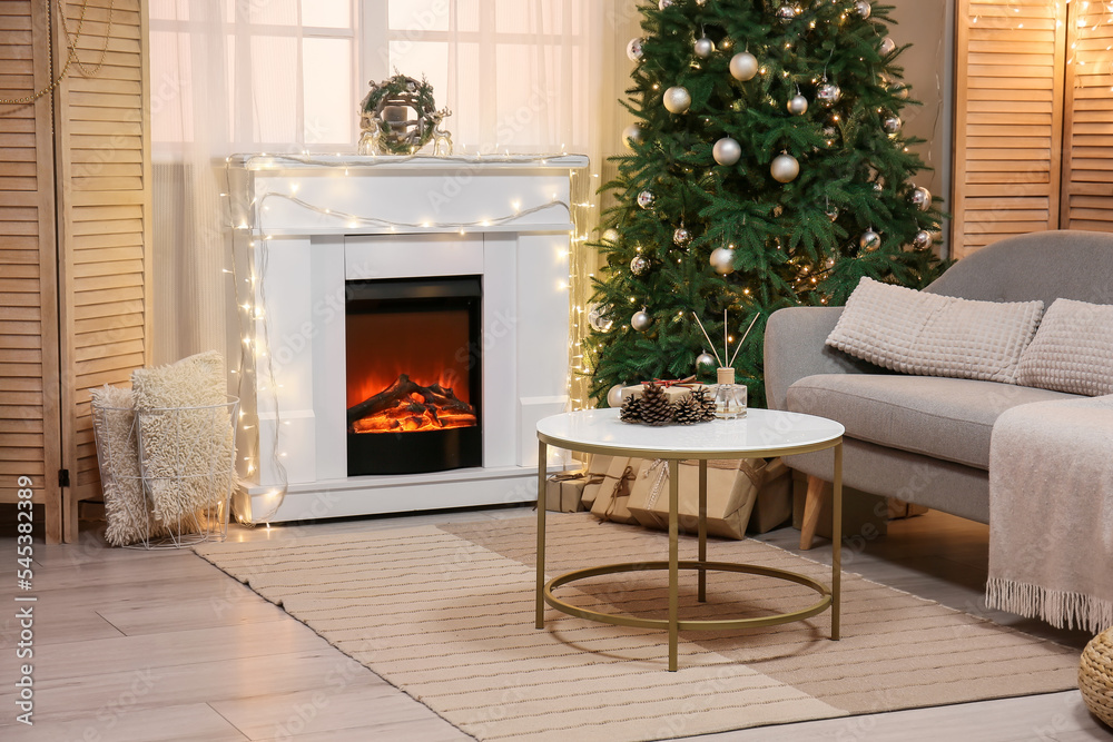 Fototapeta premium Interior of living room with fireplace, glowing lights and Christmas tree