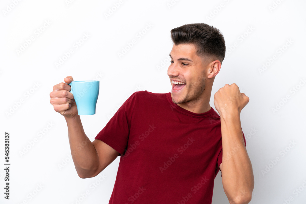 Young caucasian man holding cup of coffee isolated on white background celebrating a victory Young caucasian man holding cup of coffee isolated on white background celebrating a victory