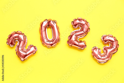 Figure 2023 made of foil balloons on yellow background