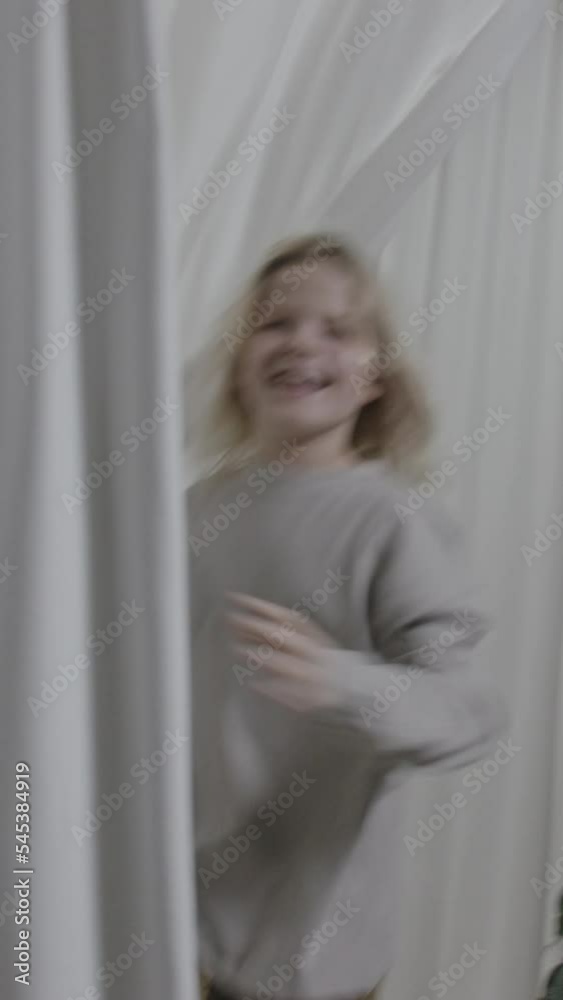 Young blond boy with long hair playing around in curtains Young blond boy with long hair playing around in curtains