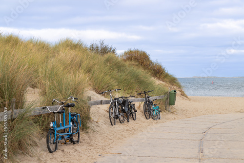 Several bicycles parked against a wooden fence in the dunes of Texel. In the background the sea and the Dutch island of Vlieland. photo