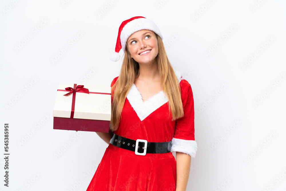 Young caucasian woman dressed as mama noel holding gift isolated on white background looking up while smiling Young caucasian woman dressed as mama noel holding gift isolated on white background looking up while smiling