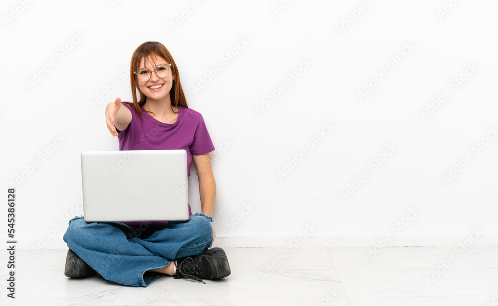 redhead girl with a laptop sitting on the floor shaking hands for closing a good deal redhead girl with a laptop sitting on the floor shaking hands for closing a good deal